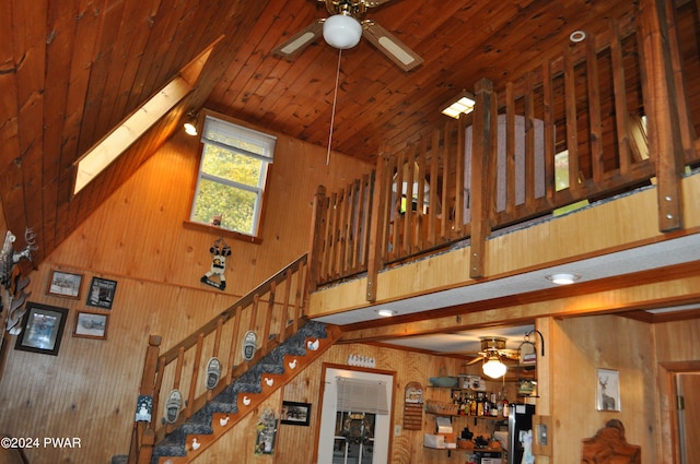 interior space featuring wooden ceiling, wood walls, and a ceiling fan