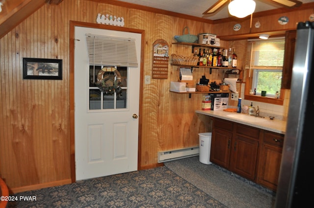 bathroom featuring ceiling fan, wood walls, a sink, baseboard heating, and crown molding