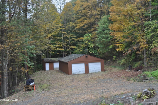 detached garage with a view of trees