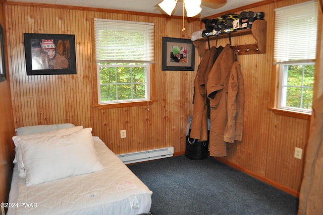 bedroom with carpet floors, wood walls, a baseboard radiator, and multiple windows