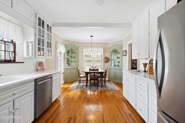 kitchen with light wood-style flooring, appliances with stainless steel finishes, white cabinets, and glass insert cabinets