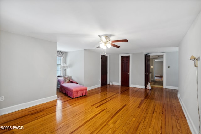 interior space featuring wood-type flooring, a ceiling fan, and baseboards