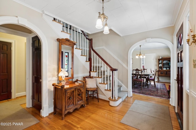entryway featuring arched walkways, a chandelier, wood finished floors, and stairway