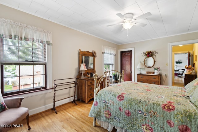 bedroom featuring crown molding, a ceiling fan, light wood-style flooring, and baseboards