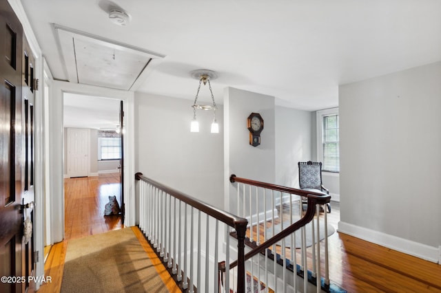 hall with plenty of natural light, attic access, wood finished floors, and an upstairs landing