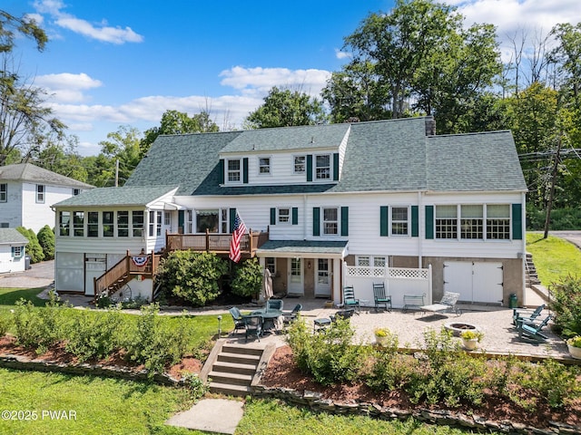 view of front of house featuring an outdoor fire pit, a wooden deck, a sunroom, stairway, and a patio