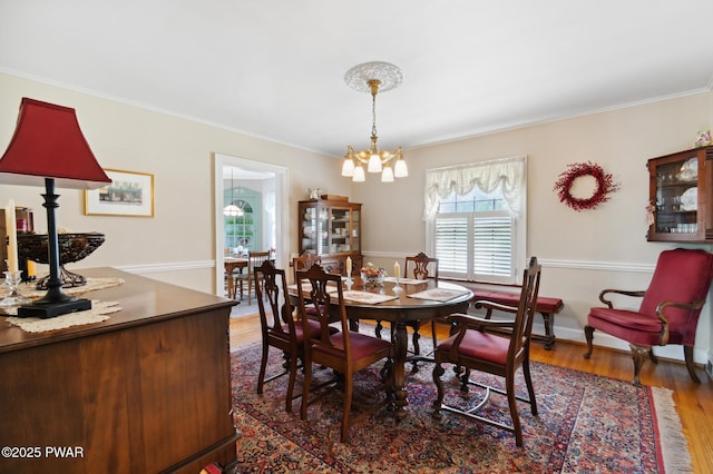 dining room with a notable chandelier, ornamental molding, and wood finished floors