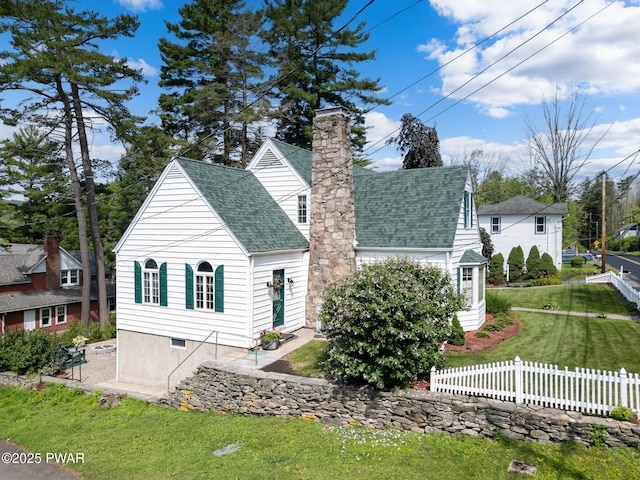 view of front of house featuring a shingled roof, a front lawn, fence, and a chimney