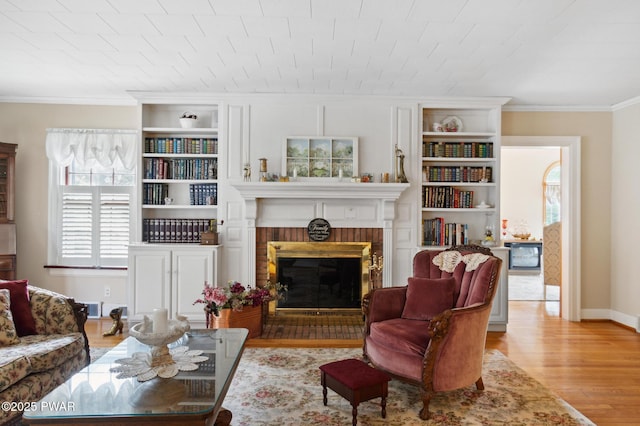 living room with baseboards, ornamental molding, a fireplace, and wood finished floors