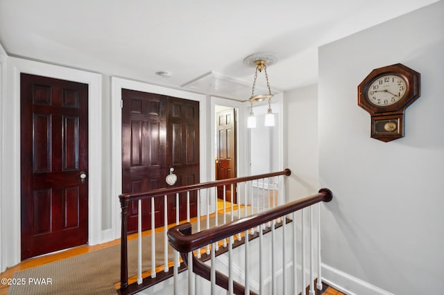 hallway with baseboards, wood finished floors, and an upstairs landing