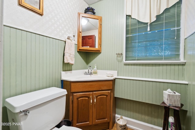 bathroom featuring vanity, toilet, and wallpapered walls