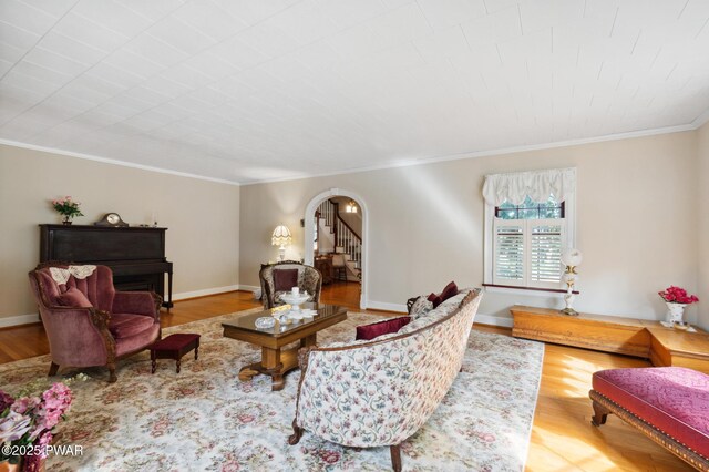living area featuring arched walkways, ornamental molding, and wood finished floors