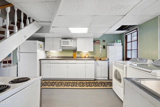 interior space featuring a paneled ceiling, concrete floors, white appliances, white cabinetry, and washer and dryer