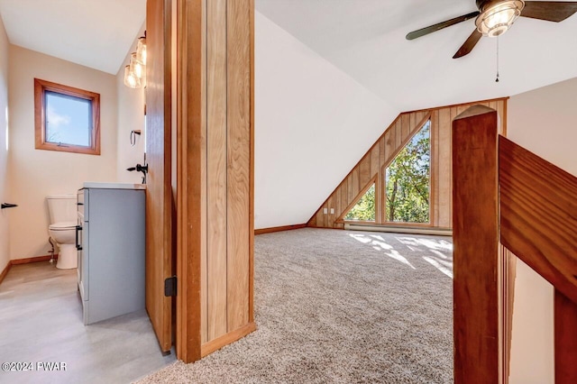 additional living space with wooden walls, light colored carpet, ceiling fan, and lofted ceiling