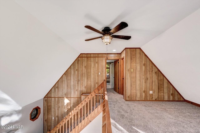 additional living space featuring carpet, vaulted ceiling, ceiling fan, and wooden walls