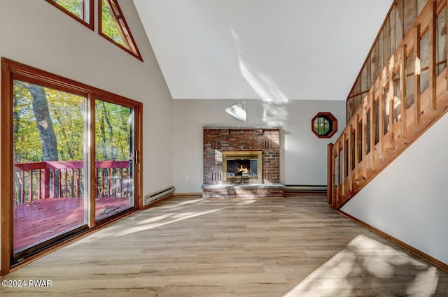 unfurnished living room with wood-type flooring, high vaulted ceiling, a brick fireplace, and a baseboard heating unit