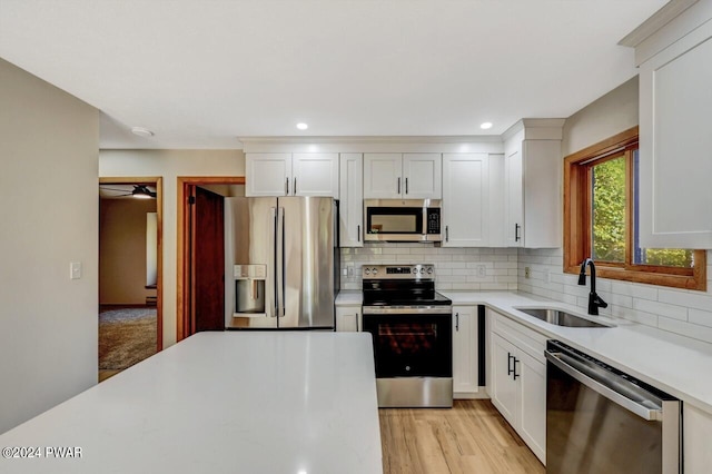 kitchen with sink, stainless steel appliances, light hardwood / wood-style flooring, decorative backsplash, and white cabinets