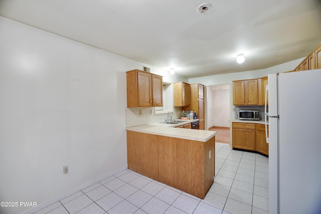 3122 Sparrow Ct, East Stroudsburg, PA 18302 - kitchen with freestanding refrigerator, stainless steel microwave, a peninsula, light tile patterned floors, and light countertops
