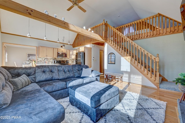 living room with sink, high vaulted ceiling, light wood-type flooring, beamed ceiling, and ceiling fan