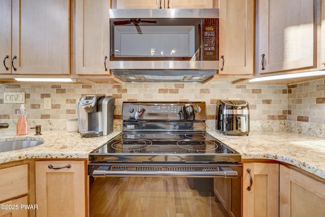 kitchen with black range with electric cooktop, light brown cabinets, and backsplash