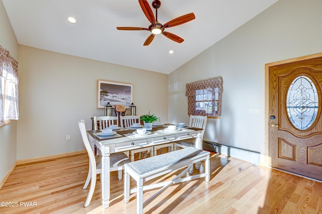 dining space featuring ceiling fan, a baseboard heating unit, vaulted ceiling, and light wood-type flooring