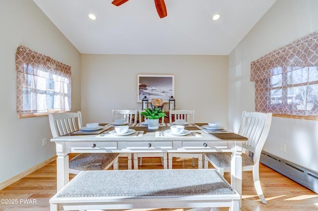 dining space with ceiling fan, a baseboard radiator, lofted ceiling, and light hardwood / wood-style floors