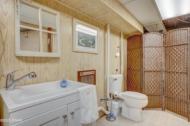 bathroom featuring toilet, vanity, and wooden walls