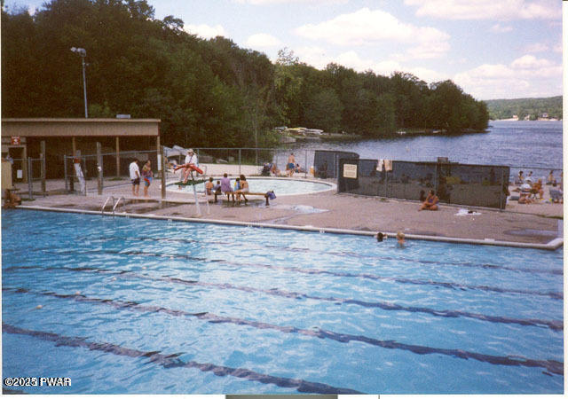 view of swimming pool featuring a patio and a water view