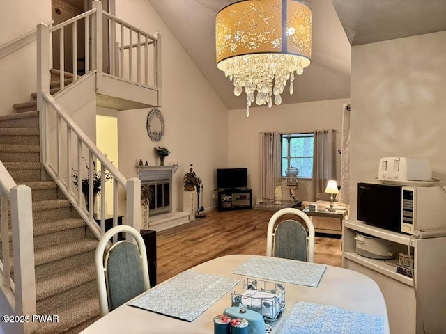 235 Falling Waters Blvd, Lackawaxen, PA 18435 - dining space featuring stairs, wood finished floors, a chandelier, and high vaulted ceiling