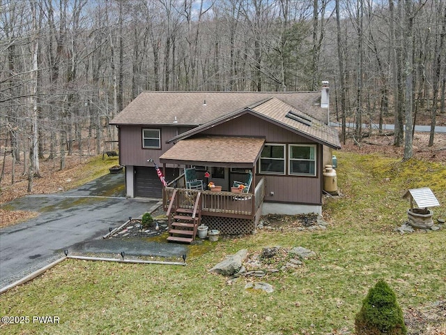 130 Grasshopper Ln, Greentown, PA 18426 - view of front of house featuring a shingled roof, asphalt driveway, an attached garage, and a forest view