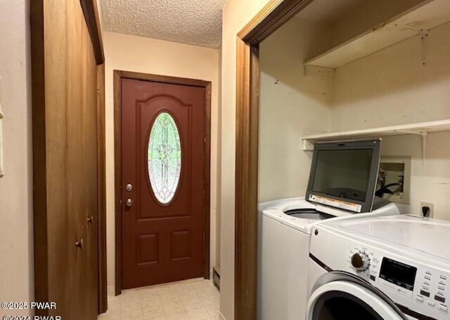 laundry room with a textured ceiling and washer and clothes dryer