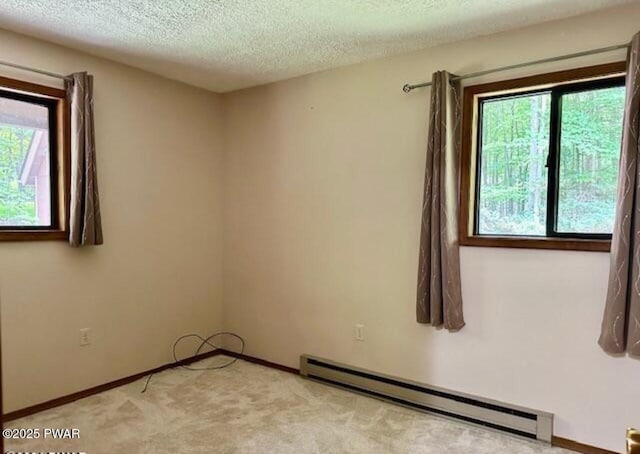 unfurnished room with light carpet, a textured ceiling, and a baseboard heating unit