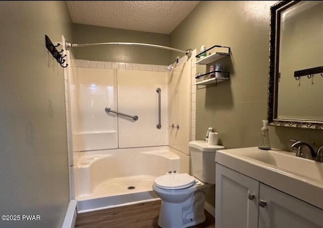 bathroom with a textured ceiling, vanity, toilet, and walk in shower