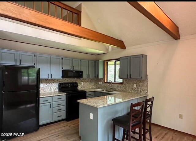 kitchen with beam ceiling, light stone countertops, sink, kitchen peninsula, and black appliances