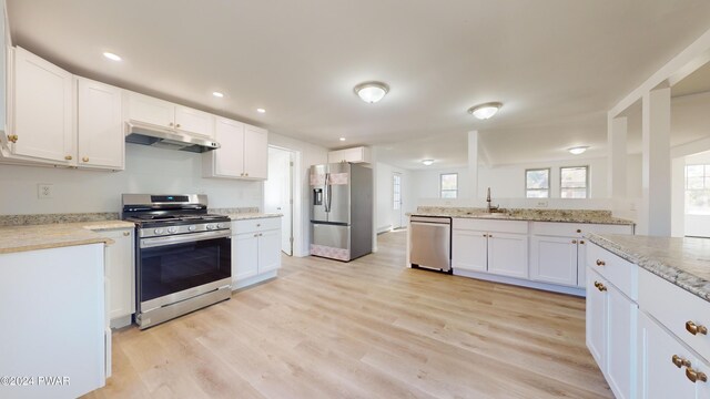 kitchen with white cabinets, sink, light hardwood / wood-style floors, light stone counters, and stainless steel appliances