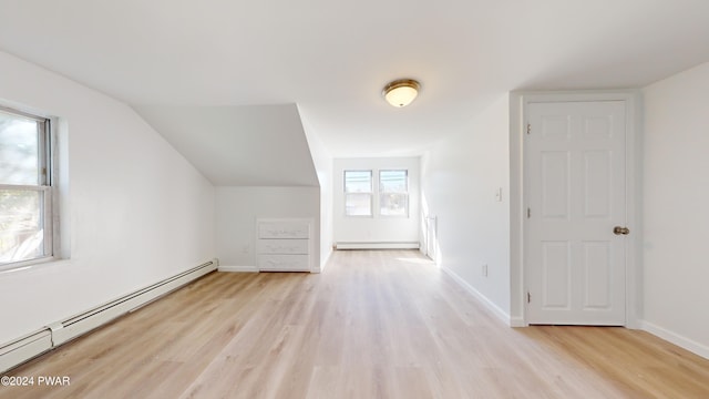 additional living space with light hardwood / wood-style floors, lofted ceiling, and a baseboard heating unit