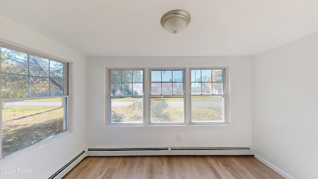 unfurnished room with a baseboard radiator and light wood-type flooring