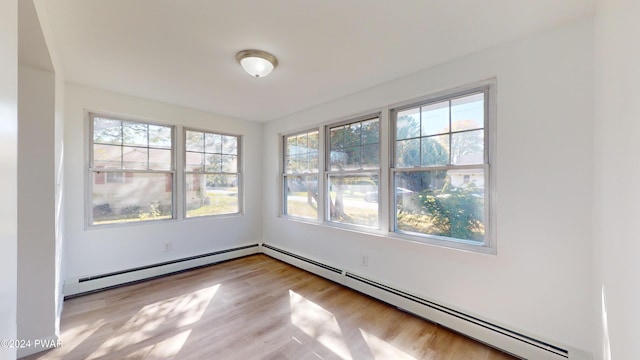 unfurnished room featuring light wood-type flooring and a baseboard heating unit