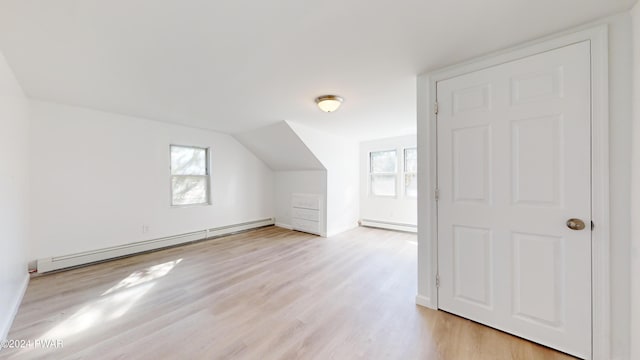 additional living space featuring light wood-type flooring, lofted ceiling, and a baseboard heating unit