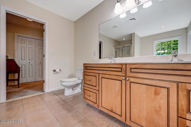 bathroom with tile patterned flooring, vanity, a shower with shower door, and toilet