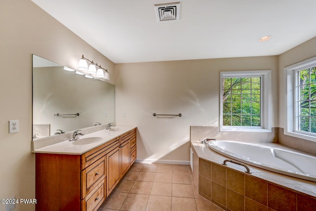 bathroom with tile patterned flooring, vanity, and a relaxing tiled tub