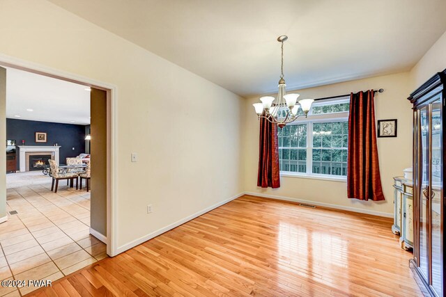 unfurnished room with light hardwood / wood-style floors and an inviting chandelier