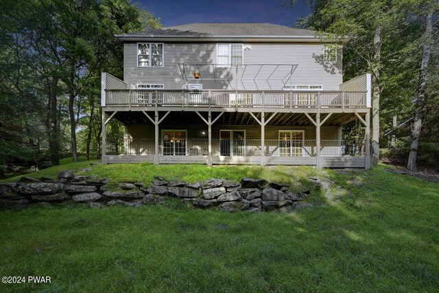 back house at dusk featuring a lawn and a wooden deck