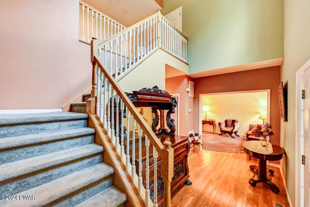 stairway with hardwood / wood-style floors and a towering ceiling