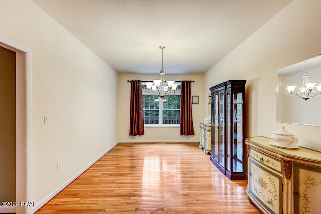 unfurnished dining area featuring light wood-type flooring and an inviting chandelier