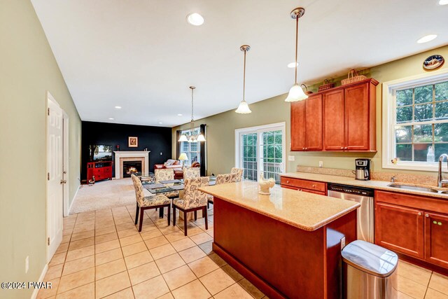 kitchen with sink, stainless steel dishwasher, light tile patterned floors, decorative light fixtures, and a kitchen island