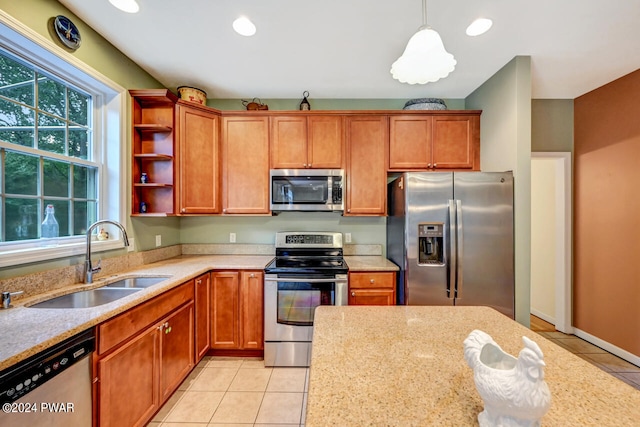 kitchen with light stone countertops, appliances with stainless steel finishes, sink, light tile patterned floors, and hanging light fixtures