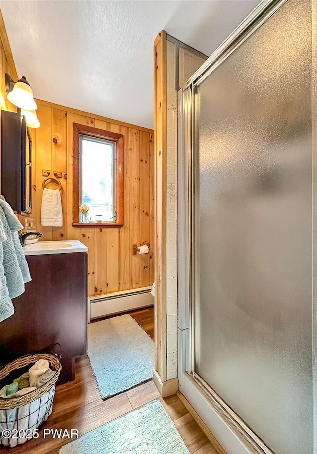 91 Bruin Rd, Lake Ariel, PA 18436 - full bathroom with baseboard heating, wood finished floors, a stall shower, and wooden walls