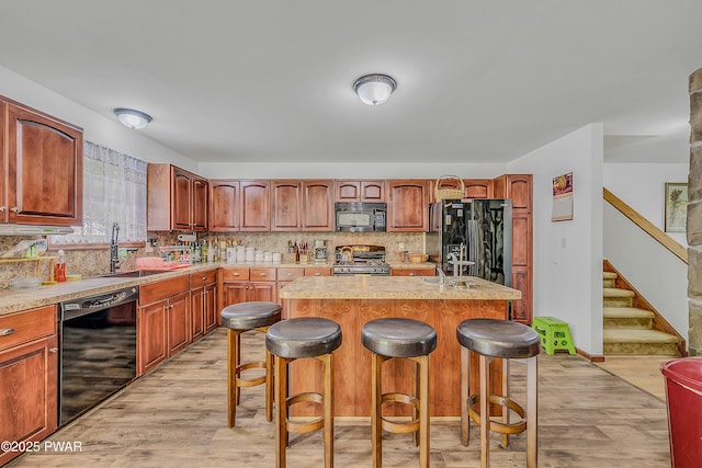 2106 Blueberry Ct, Bushkill, PA 18324 - kitchen featuring black appliances, light wood-style flooring, a breakfast bar area, and light countertops