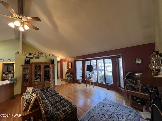 living room with ceiling fan, light hardwood / wood-style floors, and vaulted ceiling